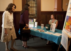 Guests arrive at information table with Nancy Black-Hernandez